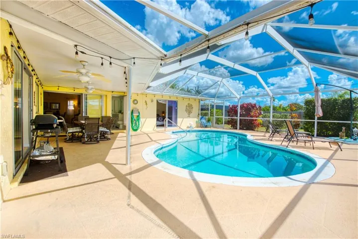 Outdoor pool featuring a patio area, a sunroom, outdoor dining area, and glass enclosure