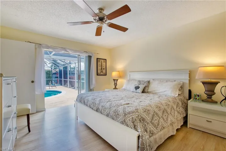 Bedroom with a sunroom, a textured ceiling, access to exterior, light wood finished floors, and ceiling fan
