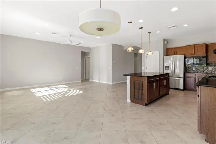 Kitchen featuring a ceiling fan, stainless steel fridge with ice dispenser, a center island, open floor plan, and pendant lighting