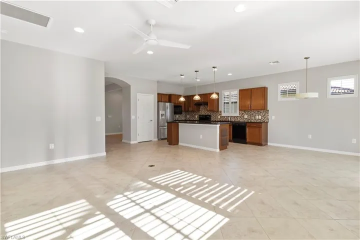 Kitchen with open floor plan, decorative light fixtures, a kitchen island, a ceiling fan, and brown cabinets