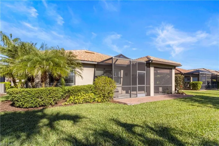 Back of house featuring a lanai, a yard, a sunroom, a tiled roof, and stucco siding