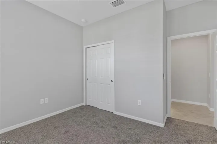 Unfurnished bedroom with light carpet and a closet