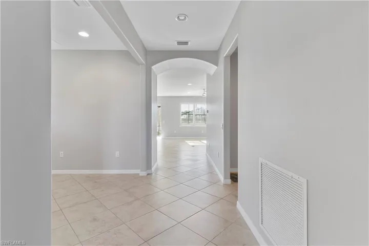 Corridor featuring arched walkways, light tile patterned flooring, and recessed lighting