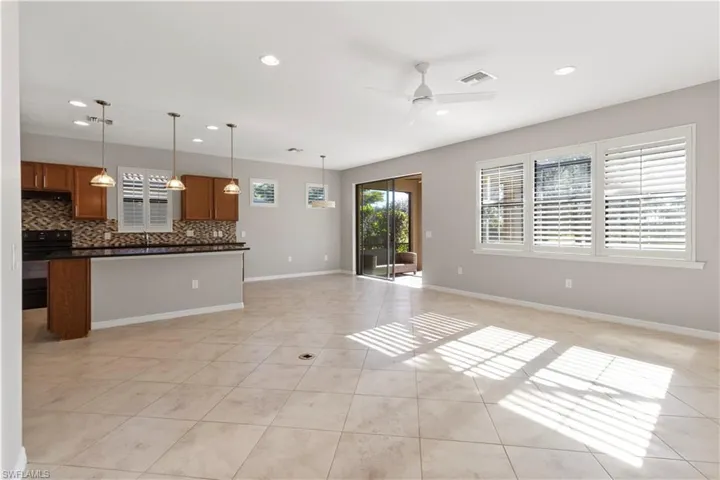 Kitchen featuring open floor plan, recessed lighting, brown cabinets, black range with electric stovetop, and decorative light fixtures
