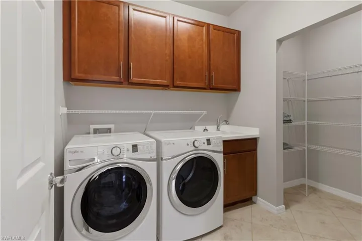 Laundry area with cabinet space, washer and clothes dryer, and light tile patterned floors