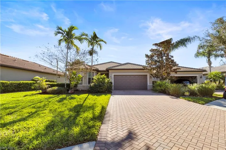 View of front of house featuring decorative driveway, a front yard, a garage, and stucco siding