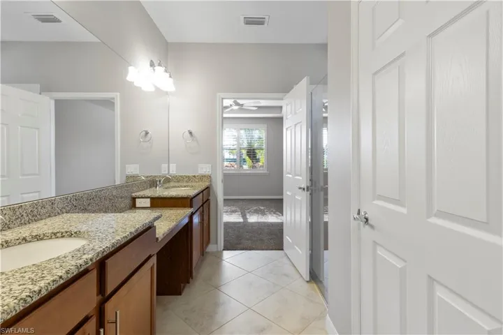Bathroom with double vanity, light tile patterned floors, and light carpet