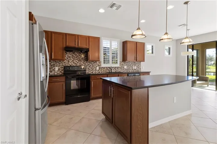 Kitchen with a kitchen island, black electric range, stainless steel fridge with ice dispenser, brown cabinets, and light tile patterned flooring