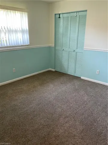Unfurnished bedroom featuring carpet flooring, baseboards, and a closet