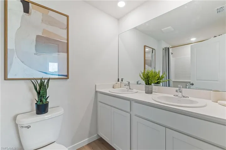 MODEL HOME - Bathroom featuring a shower stall, double vanity, and light wood-style floors
