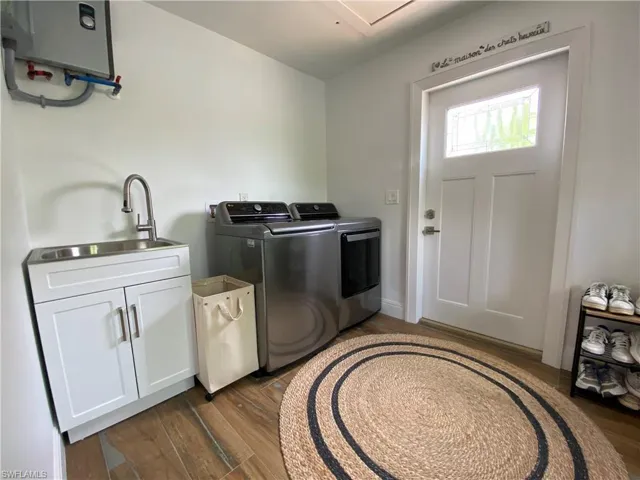 Large laundry room with tankless water heater, sink, storage and door to side patio