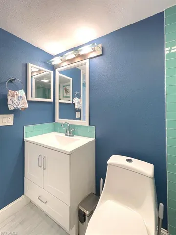 Bathroom with a textured ceiling, vanity, and a textured wall
