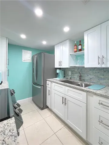 Kitchen with stainless steel refrigerator with ice dispenser, open shelves, white cabinetry, backsplash, and recessed lighting