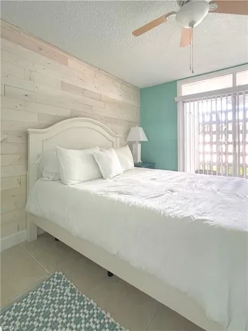 Bedroom featuring wood walls, a textured ceiling, and a ceiling fan