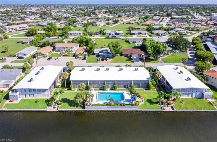 Aerial perspective of suburban area with a pool area and a large body of water