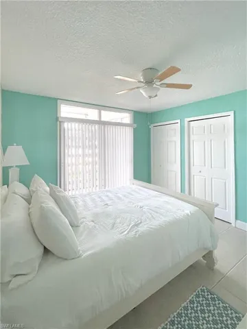Bedroom with two closets, ceiling fan, and a textured ceiling
