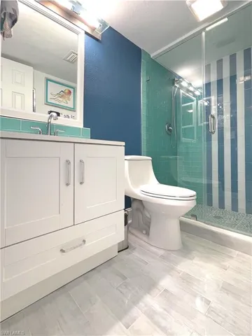 Full bath with a shower stall, vanity, and a textured wall