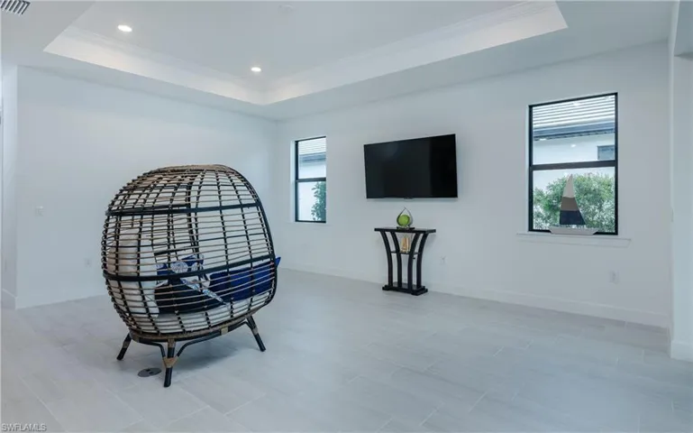 Sitting room with ornamental molding, recessed lighting, and a tray ceiling