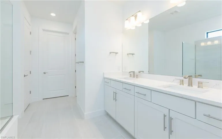 Full bath with a shower stall, double vanity, and recessed lighting