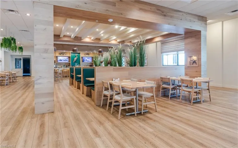 Dining room with beam ceiling, light wood finished floors, wood walls, and recessed lighting