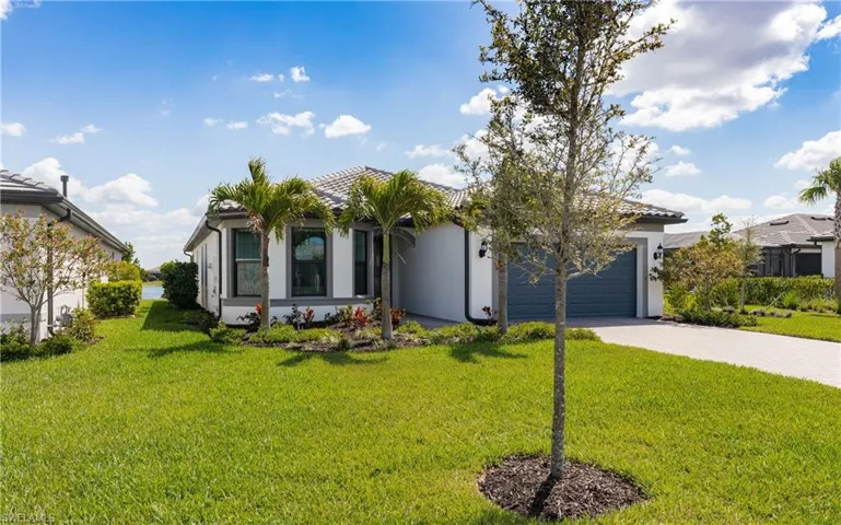 View of front of property featuring a front lawn, stucco siding, decorative driveway, and an attached garage