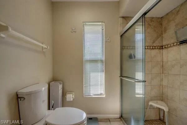 Bathroom with tile patterned floors, toilet, and walk in shower