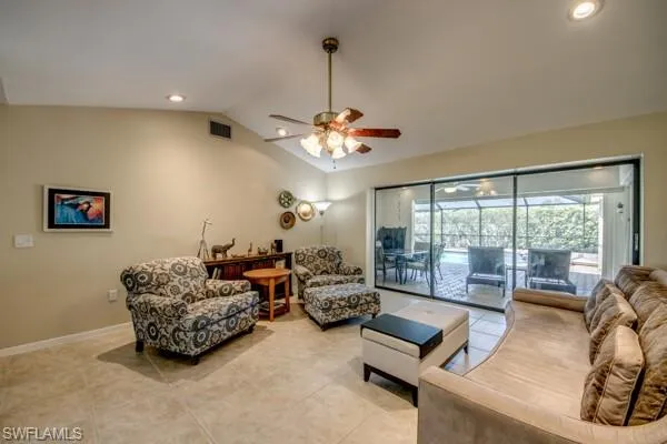Living room with ceiling fan, light tile patterned flooring, and lofted ceiling