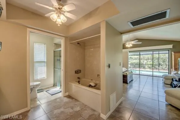 Bathroom with shower with separate bathtub, ceiling fan, toilet, tile patterned floors, and lofted ceiling