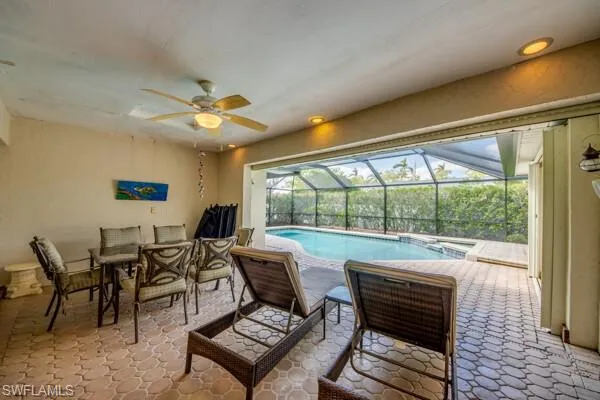 View of pool featuring a patio, glass enclosure, and ceiling fan