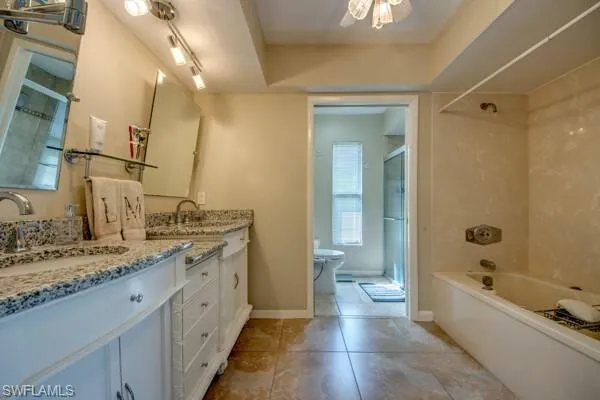 Full bathroom featuring tile patterned floors, toilet,  shower combination, vanity, and ceiling fan