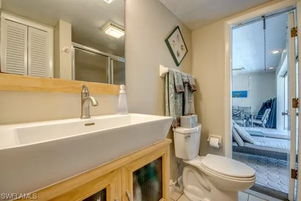 Bathroom with toilet, an enclosed shower, vanity, and tile patterned floors