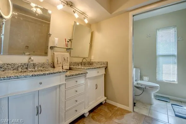 Bathroom featuring vanity, toilet, tile patterned floors, and a wealth of natural light