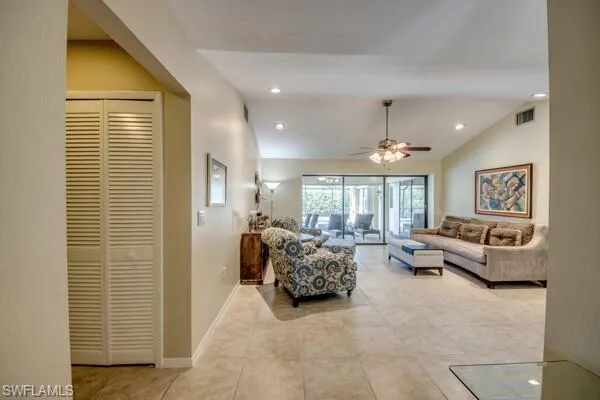 Tiled living room with ceiling fan and vaulted ceiling