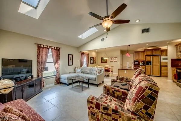 Living room with sink, ceiling fan, high vaulted ceiling, and light tile patterned floors