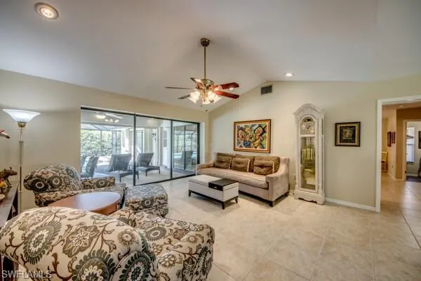Tiled living room featuring ceiling fan and vaulted ceiling