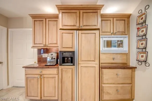 Kitchen with light brown cabinets, paneled refrigerator, tasteful backsplash, and light tile patterned floors