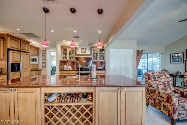 Kitchen with a large island, custom range hood, decorative light fixtures, and built in appliances