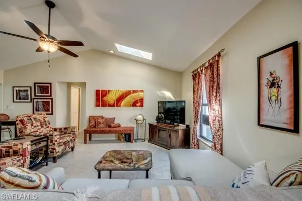 Living room featuring vaulted ceiling with skylight and ceiling fan