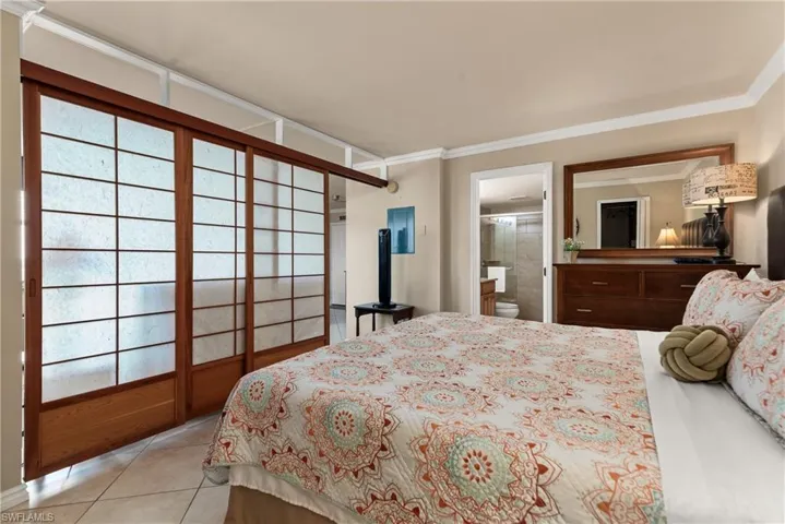 Bedroom with ornamental molding, light tile patterned flooring