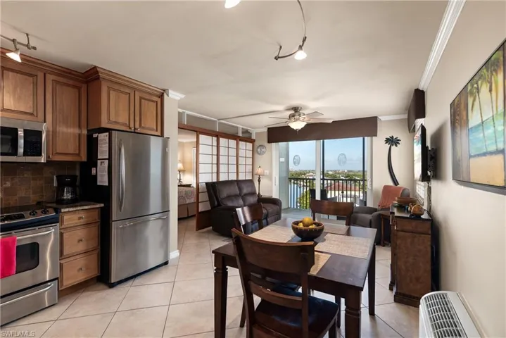 Kitchen featuring appliances with stainless steel finishes, rail lighting, wood cabinetry, light tile flooring, and tasteful backsplash