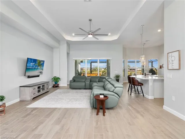 Living room with a ceiling fan, wood tiled floors, a raised ceiling, and recessed lighting