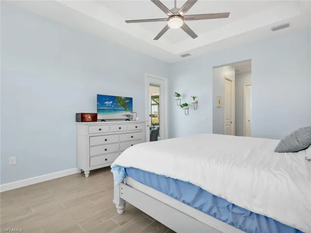 Bedroom featuring a raised ceiling, wood tiled floors, and ceiling fan