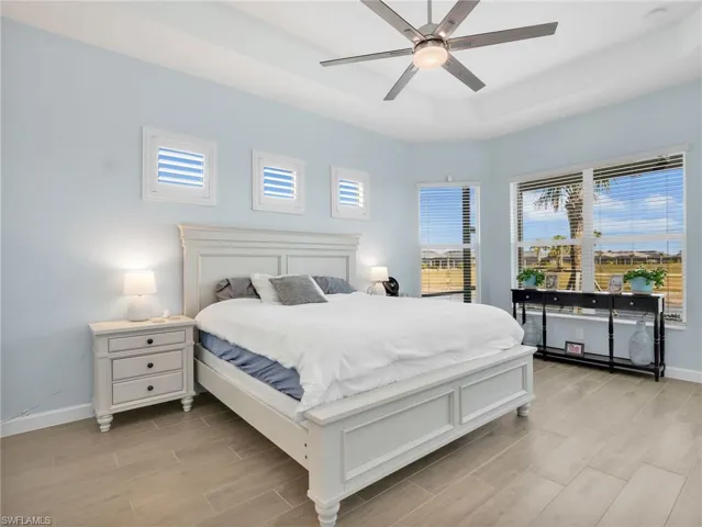 Bedroom featuring a raised ceiling, wood finish floors, and ceiling fan