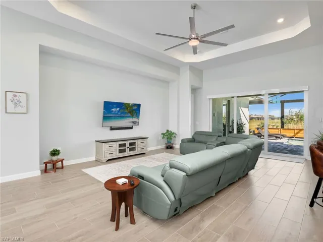 Living area featuring ceiling fan, wood tiled floors, and a raised ceiling
