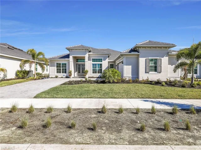 Prairie-style house with a front lawn, driveway, a tile roof, and stucco siding