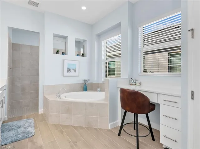 Bathroom with a bath, vanity, wood tiled floors, and recessed lighting