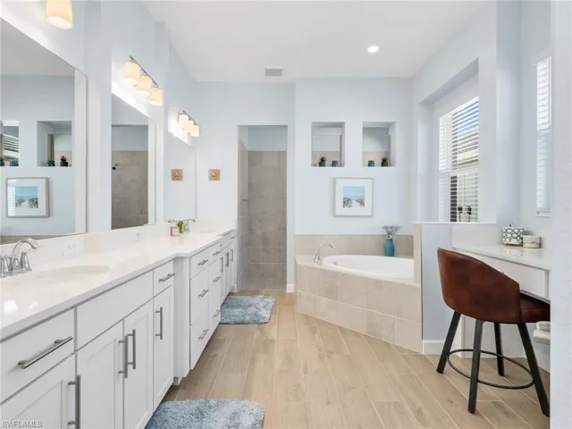 Bathroom with a garden tub, double vanity, walk in shower, and light wood finished floors