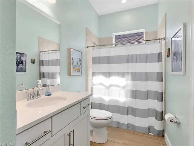 Bathroom featuring vanity, a shower with curtain, wood finish floors, and a textured wall