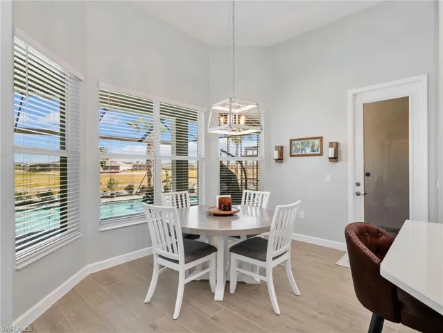 Dining room with light wood-style flooring, a chandelier, and a high ceiling