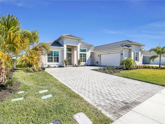 View of front of home with a front lawn, decorative driveway, an attached garage, stucco siding, and a tiled roof